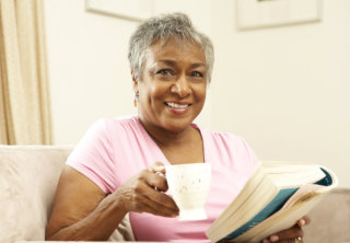 old woman reading a book while drinking a coffee